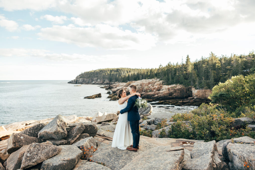 A bride and groom standing on the edge of Ocean Path Trail in Acadia National Park, Bar Harbor Maine